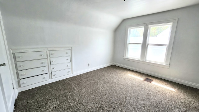 bonus room with lofted ceiling, dark colored carpet, and baseboards