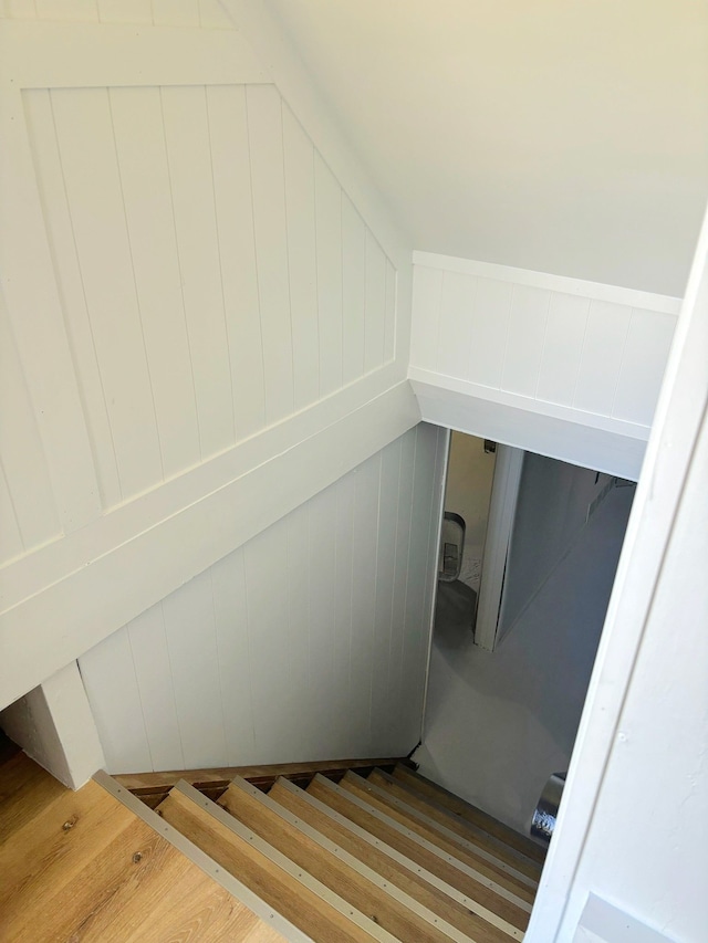 staircase featuring a decorative wall and wood finished floors