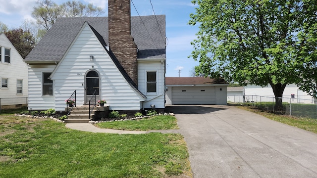 bungalow-style home featuring a chimney, roof with shingles, and a detached garage
