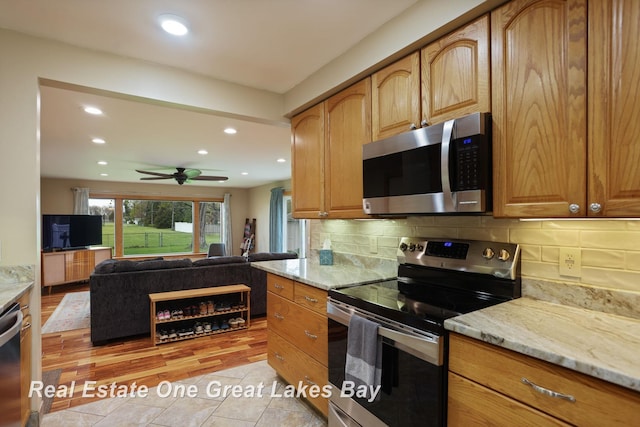 1416 Airfield Ln, Midland, MI 48642 - kitchen featuring appliances with stainless steel finishes, light stone counters, recessed lighting, open floor plan, and backsplash