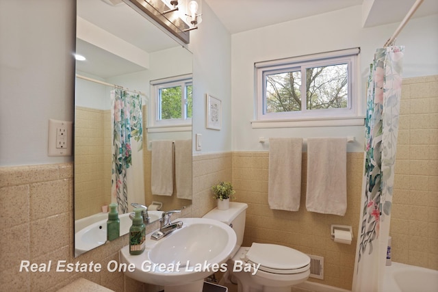 1416 Airfield Ln, Midland, MI 48642 - bathroom featuring tile walls, wainscoting, toilet, a sink, and shower / bath combo with shower curtain