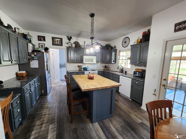 kitchen with white appliances, wood counters, a center island, dark wood-style flooring, and a kitchen breakfast bar