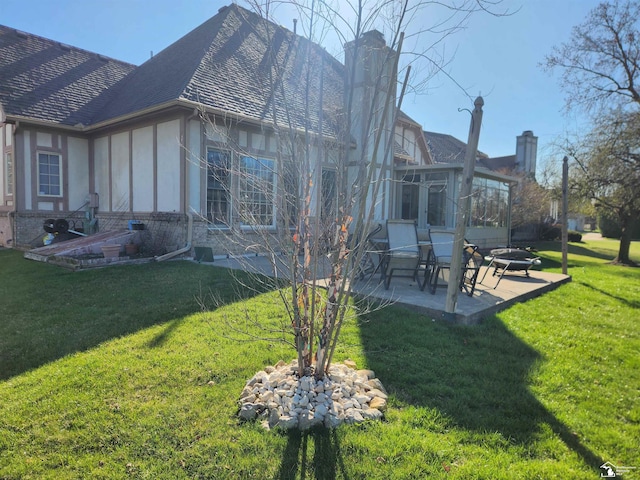 back of house with a sunroom, a patio area, a lawn, a chimney, and a fire pit