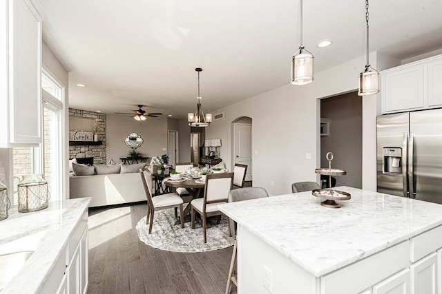 kitchen featuring a ceiling fan, arched walkways, dark wood-style flooring, a kitchen island, and white cabinetry