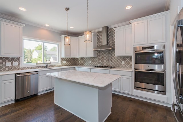 kitchen with stainless steel appliances, wall chimney range hood, a sink, dark wood finished floors, and crown molding