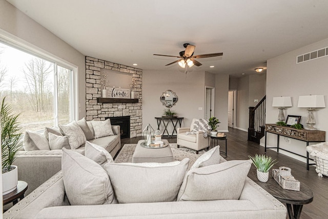living area featuring dark wood-style floors, ceiling fan, stairway, and a fireplace