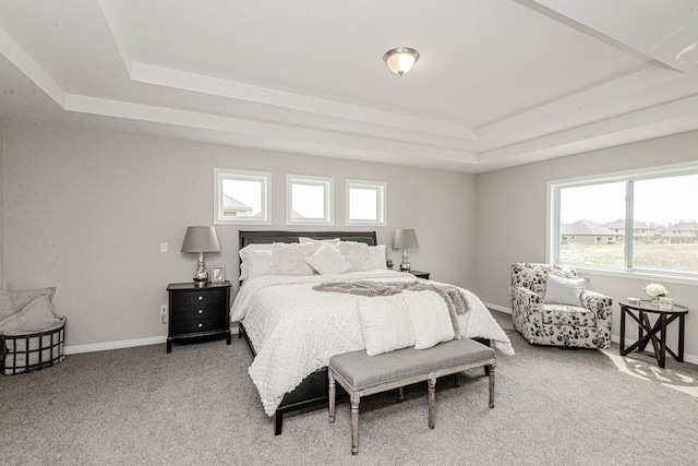 bedroom featuring a tray ceiling, light colored carpet, multiple windows, and baseboards
