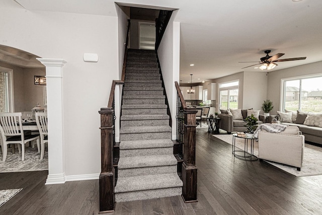 staircase with wood finished floors, ceiling fan, arched walkways, baseboards, and recessed lighting