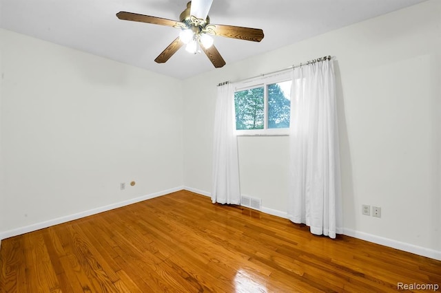 spare room featuring wood finished floors, baseboards, and a ceiling fan