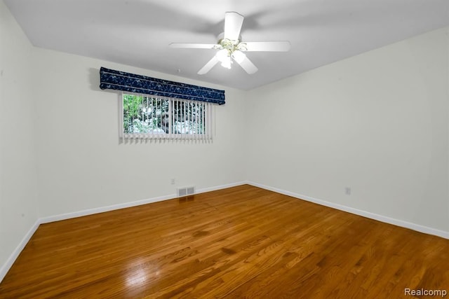 empty room with wood finished floors, baseboards, and a ceiling fan