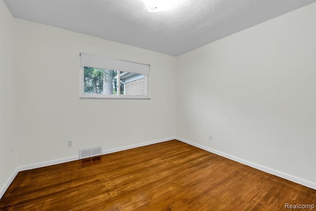 empty room featuring wood finished floors and baseboards