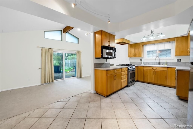 kitchen featuring stainless steel appliances, light colored carpet, light countertops, a sink, and brown cabinetry