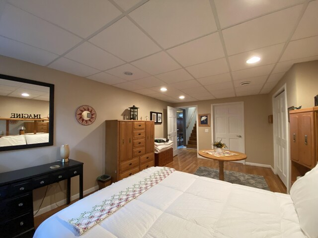 bedroom with wood finished floors, recessed lighting, a drop ceiling, and baseboards