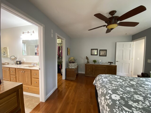 bedroom with a walk in closet, a sink, light wood-style flooring, ensuite bathroom, and a closet