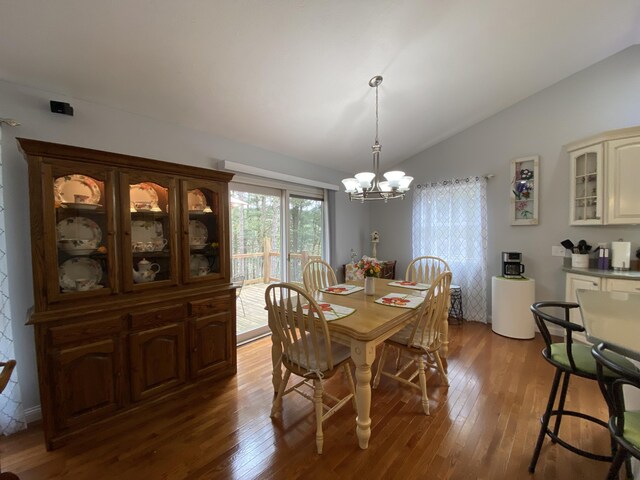 dining area with lofted ceiling, a chandelier, and wood finished floors