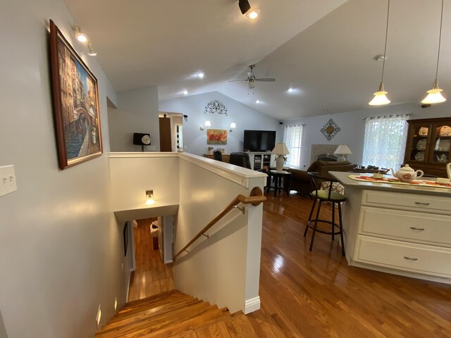 staircase with ceiling fan, vaulted ceiling, and wood finished floors