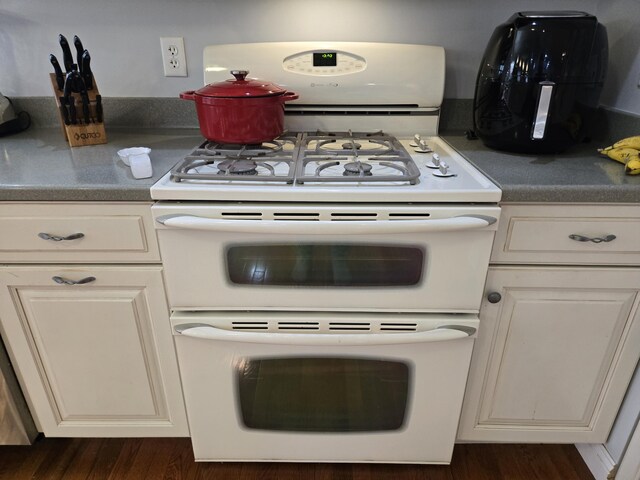 kitchen featuring double oven range, dark wood-style flooring, and dark countertops