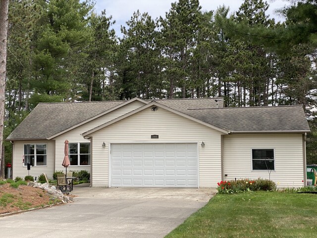 ranch-style house with an attached garage, driveway, and roof with shingles