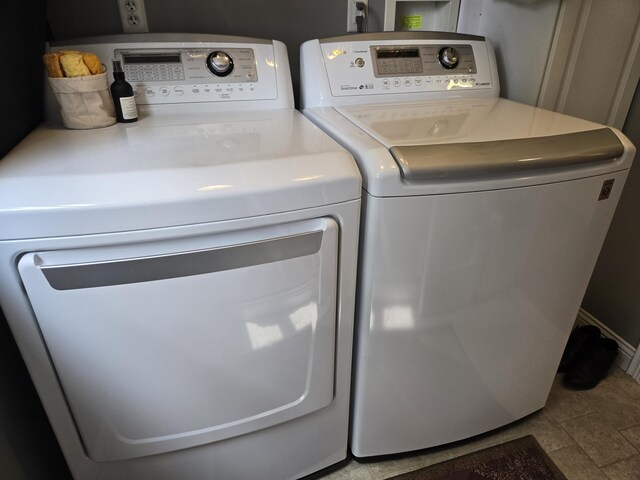 clothes washing area featuring separate washer and dryer and stone finish flooring