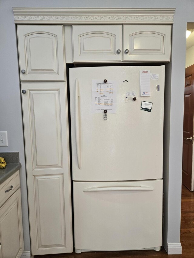 kitchen with freestanding refrigerator, cream cabinetry, and dark countertops
