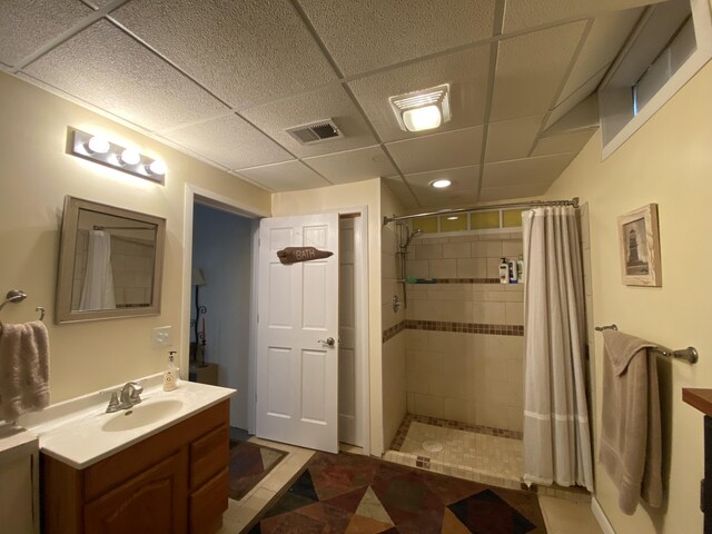 full bath with a tile shower, vanity, a drop ceiling, and recessed lighting