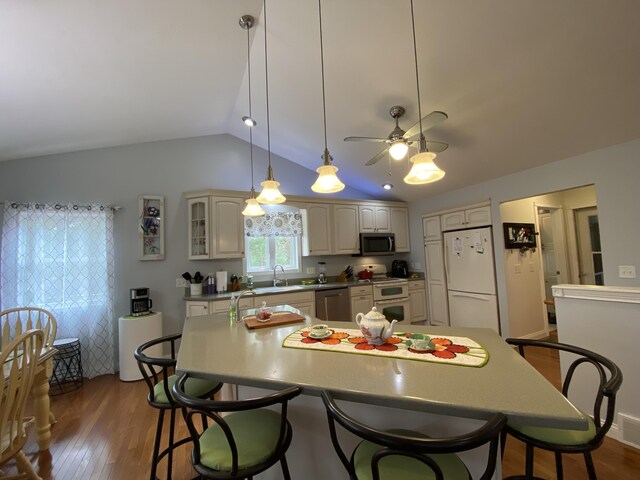 kitchen with appliances with stainless steel finishes, a kitchen breakfast bar, lofted ceiling, dark wood-style floors, and a sink