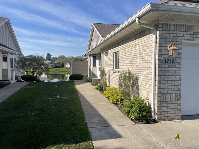 1712 Lisa Dr SW, Byron Center, MI 49315 - view of home's exterior with brick siding, a lawn, an attached garage, a water view, and roof with shingles