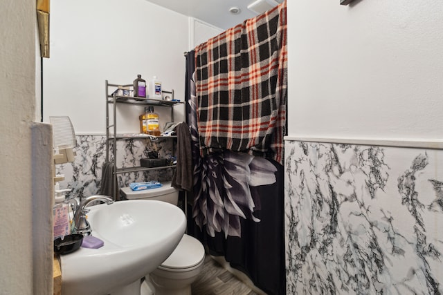 full bath featuring toilet, a sink, a shower with curtain, a wainscoted wall, and wood finished floors