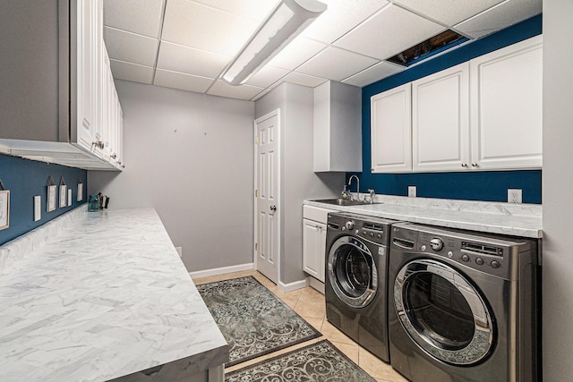 washroom featuring washer and dryer, cabinet space, light tile patterned flooring, and baseboards