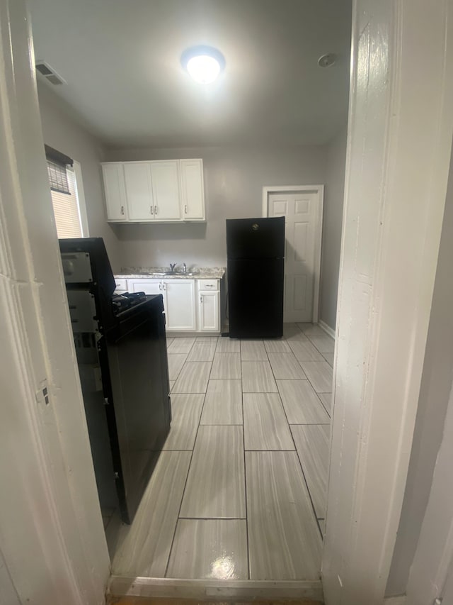 2135 Lakewood St, Detroit, MI 48215 - kitchen featuring freestanding refrigerator, light countertops, white cabinets, a sink, and baseboards