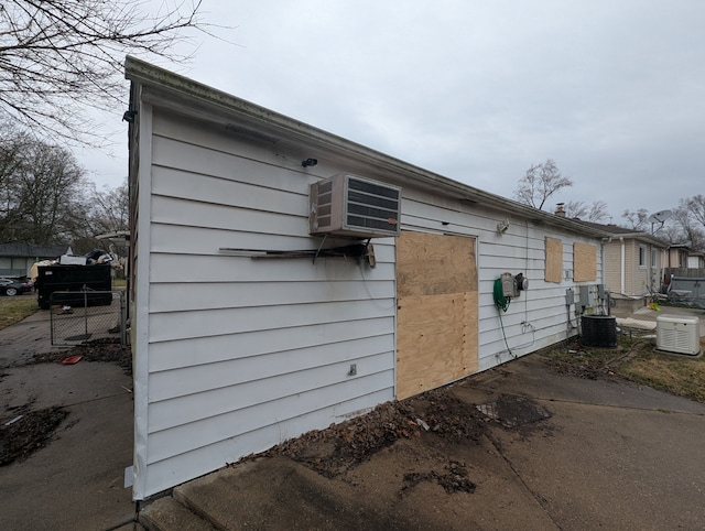 view of side of property with fence, cooling unit, and an AC wall unit