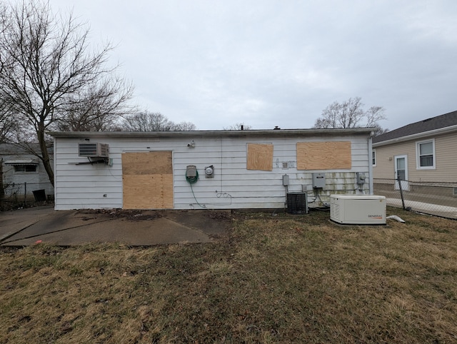back of house with central air condition unit and a wall mounted air conditioner