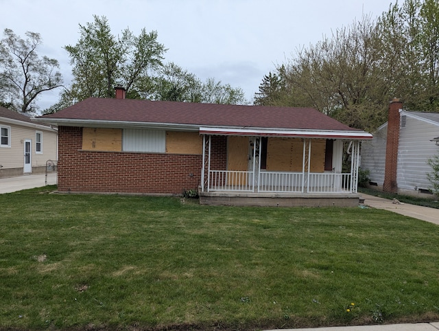 view of front facade with covered porch, brick siding, and a front yard