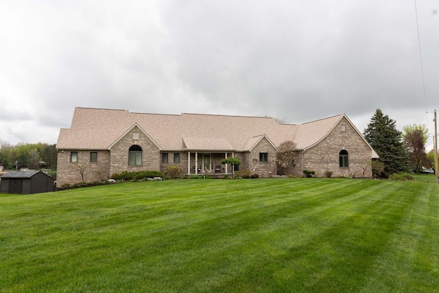 view of front of property featuring a front yard, a storage shed, an outdoor structure, and brick siding