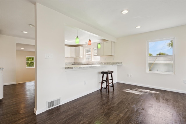 25034 Redfield St, Edwardsburg, MI 49112 - kitchen with dark wood-type flooring, a breakfast bar area, white cabinets, recessed lighting, and light countertops