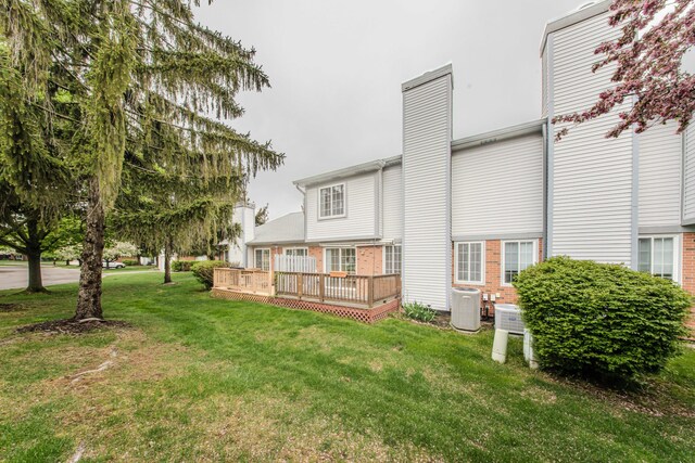 back of property featuring a deck, a chimney, central AC, and a yard