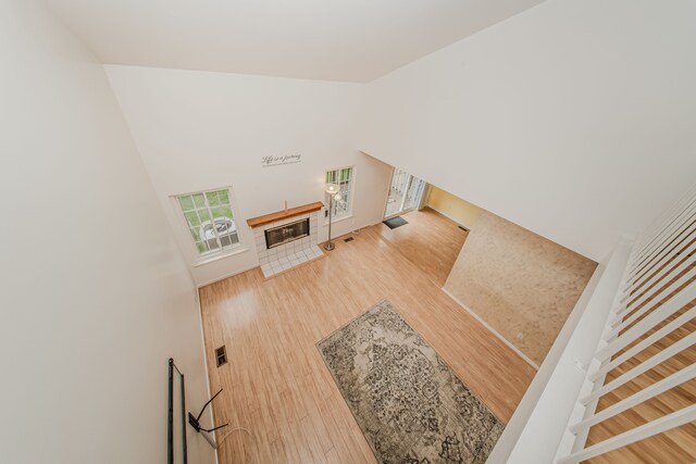stairway featuring wood finished floors, a glass covered fireplace, baseboards, and high vaulted ceiling