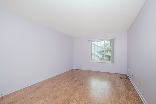 empty room featuring light wood finished floors and baseboards