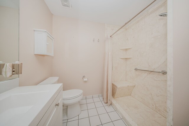 full bathroom featuring toilet, a tile shower, vanity, and tile patterned floors