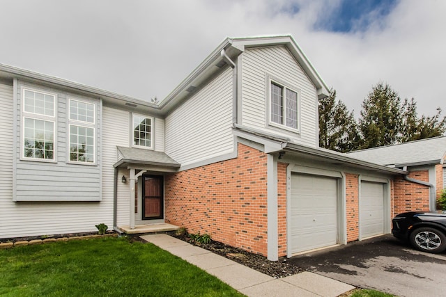 view of front of property with driveway, brick siding, a garage, and a front yard