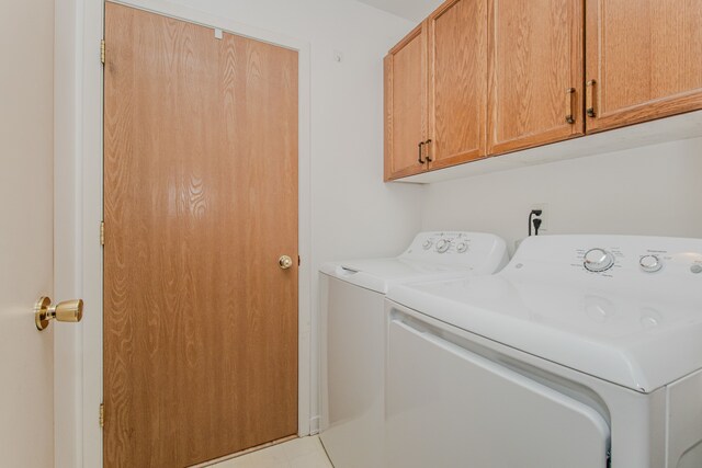 clothes washing area featuring independent washer and dryer and cabinet space