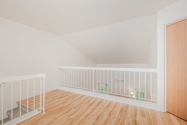 additional living space featuring wood finished floors, lofted ceiling, and baseboards