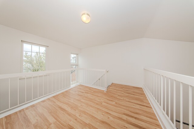 bonus room with light wood-type flooring, a baseboard heating unit, and vaulted ceiling