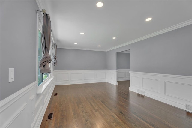 empty room featuring recessed lighting, wainscoting, crown molding, wood finished floors, and a decorative wall
