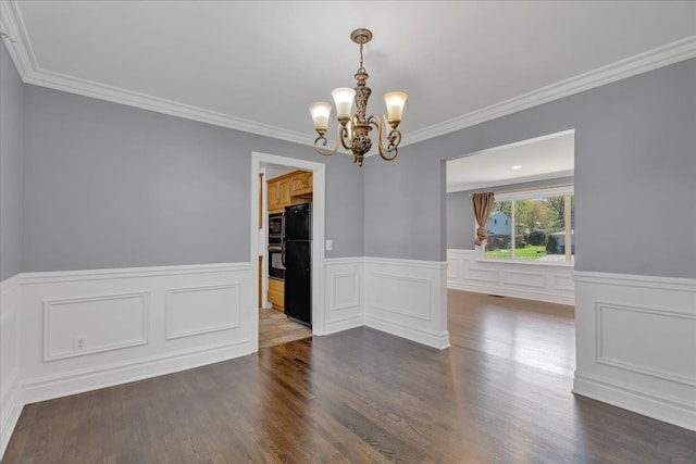 unfurnished dining area featuring a chandelier, wood finished floors, wainscoting, and ornamental molding