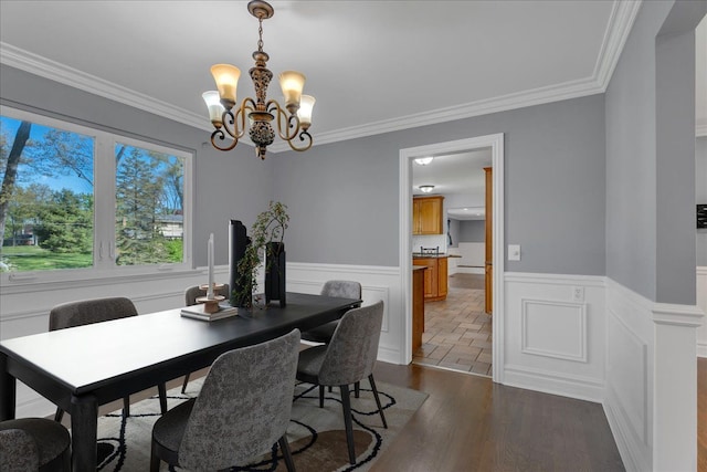 dining room with wainscoting, a chandelier, ornamental molding, and wood finished floors