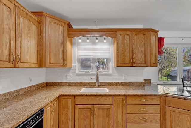 kitchen featuring a sink, black dishwasher, decorative backsplash, and light stone countertops