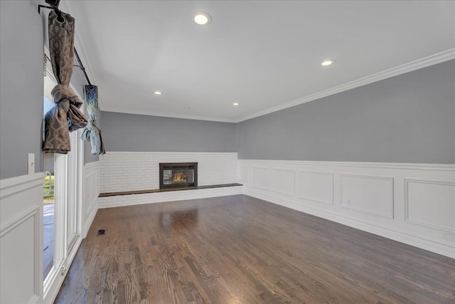 unfurnished living room featuring wainscoting, a brick fireplace, recessed lighting, ornamental molding, and wood finished floors