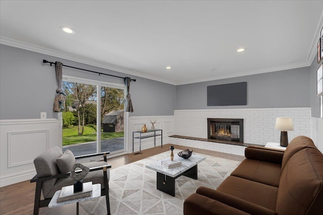 living area featuring a fireplace, a wainscoted wall, recessed lighting, wood finished floors, and crown molding