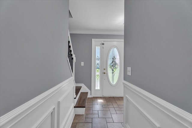 foyer entrance featuring stone tile flooring, stairway, and crown molding